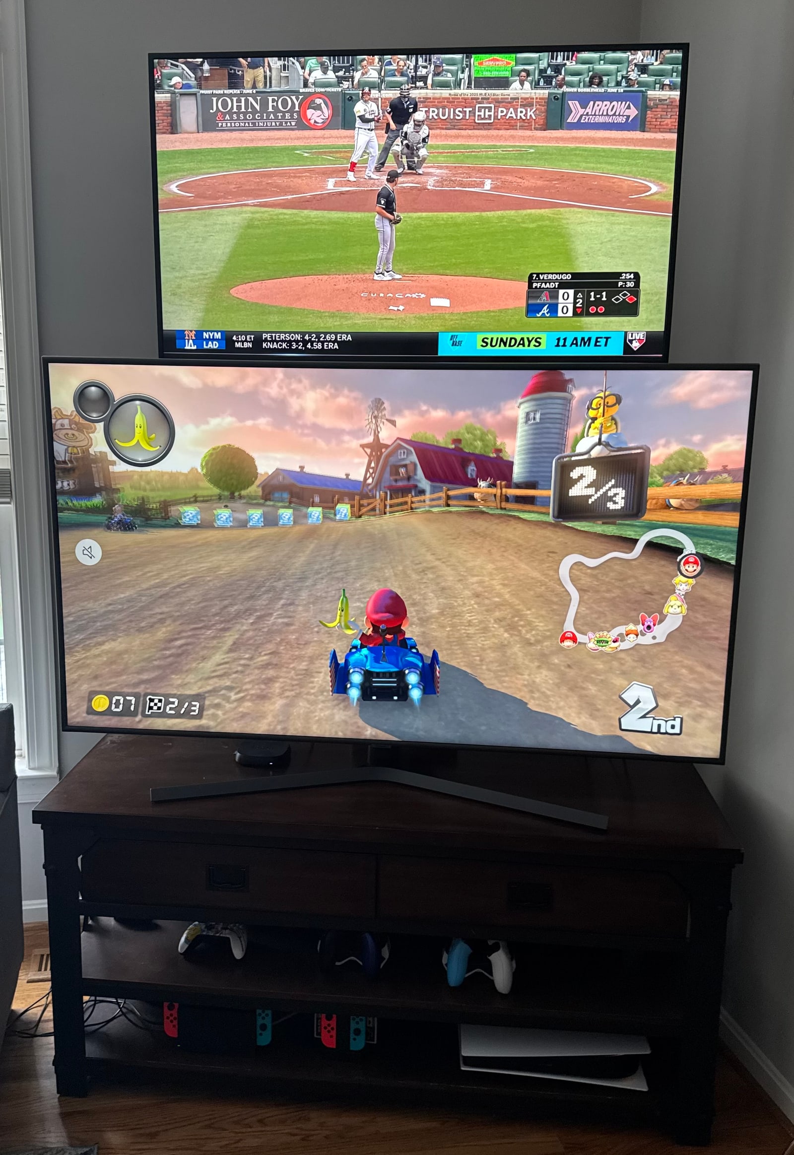 Mario Kart on the main screen with a baseball game on the raised second TV